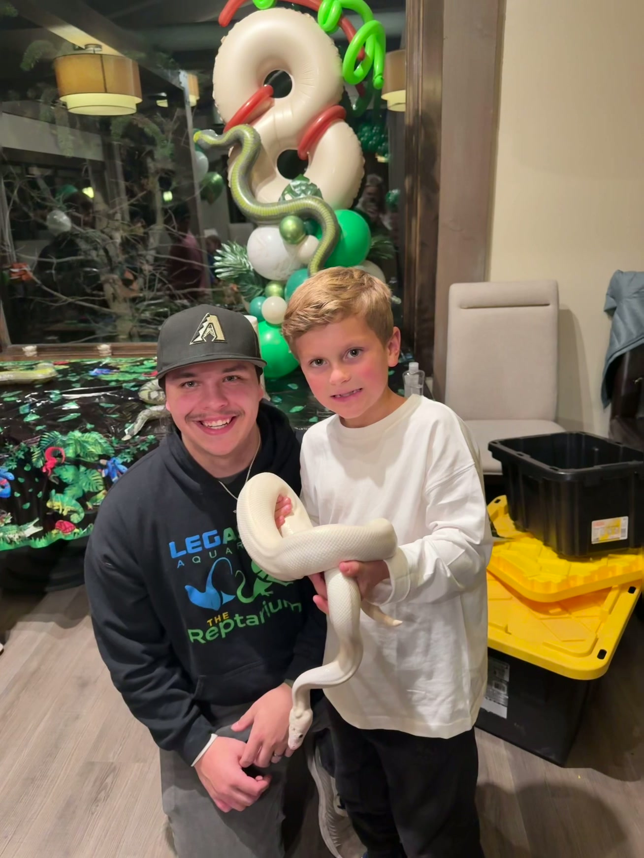 XP Reptiles handler and a child holding a white ball python at a birthday party